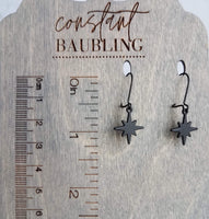 Black Star Earrings, small matte black sunburst charm, latching kidney hooks, night earrings, celestial earring starburst earring north star - Constant Baubling